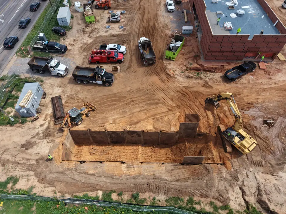 Shored tank excavation with equipment and dump trucks on site