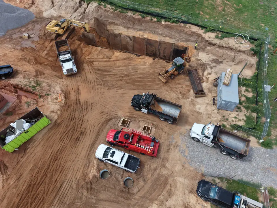 Equipment and trucks staged beside the shored excavation