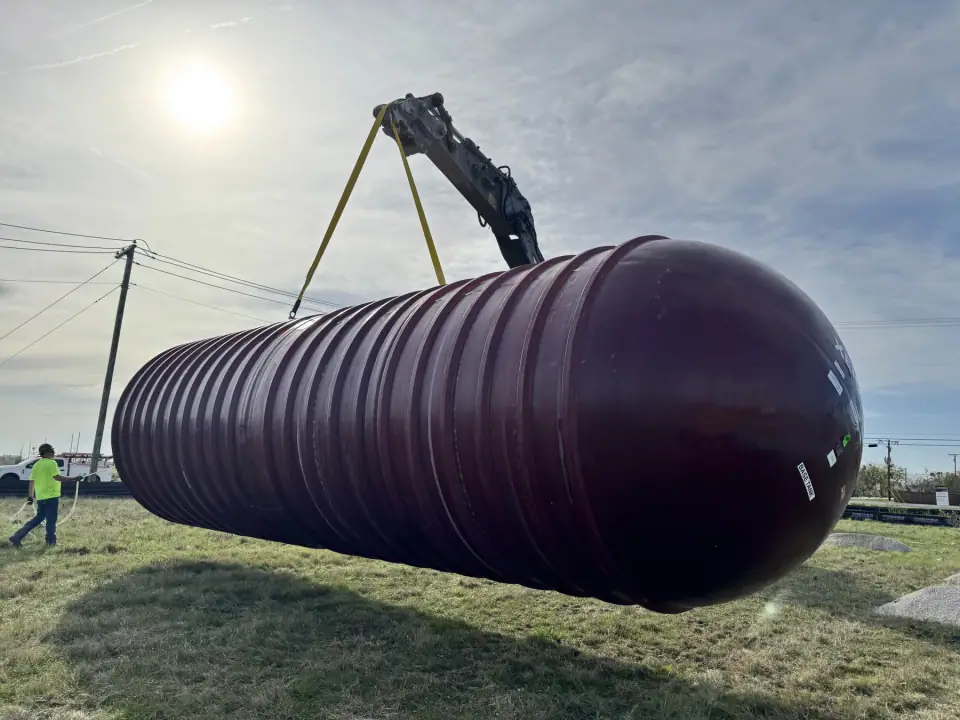 Underground storage tank suspended from the excavator during unloading