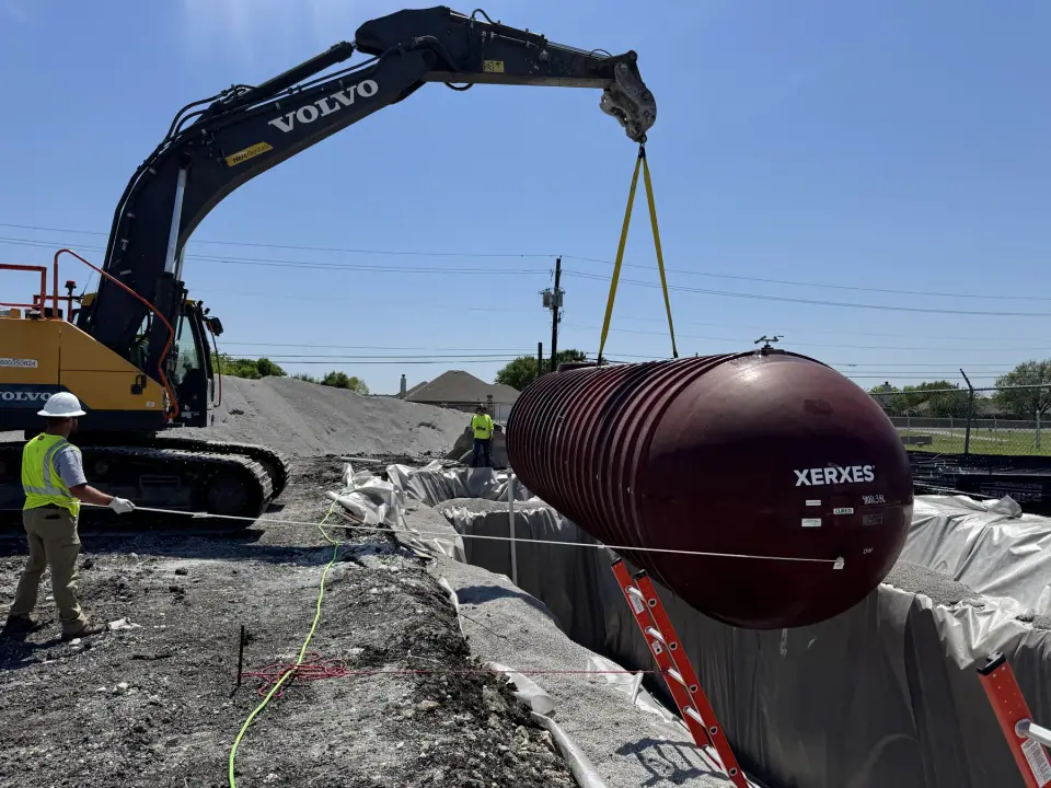 Tank lowered into the lined excavation, guided by tagline