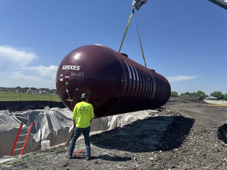 Crew member guiding a tank toward the excavation