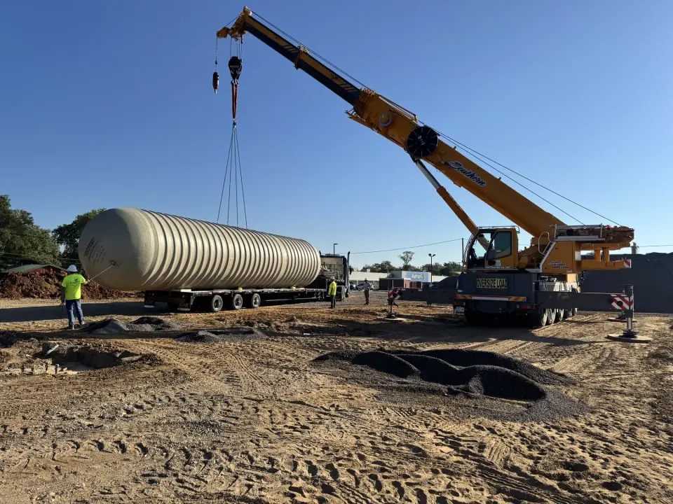 Crane lifting a fiberglass tank off the trailer