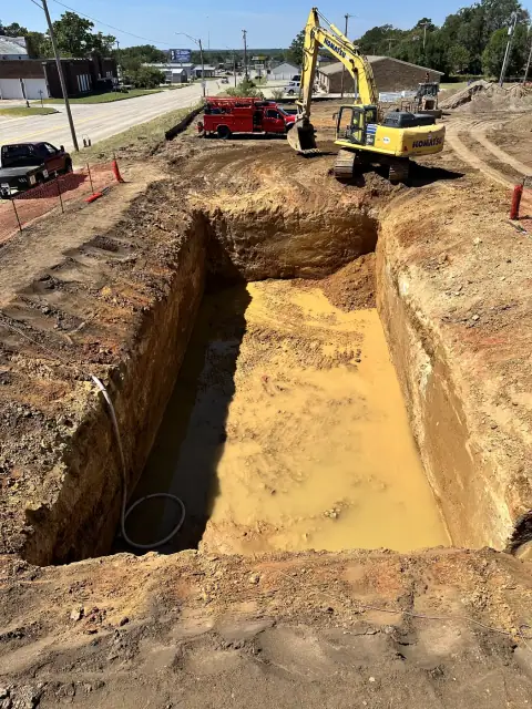 Tank excavation with an excavator and dump trucks