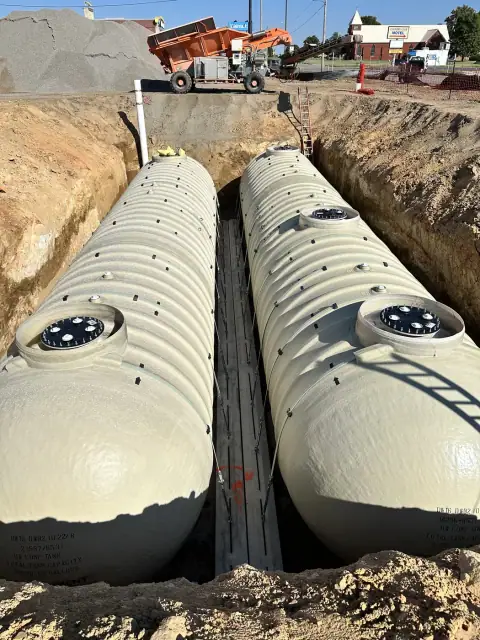 Two fiberglass tanks set side by side in the excavation