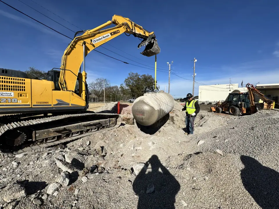 Excavator lifting the old underground tank from the pit